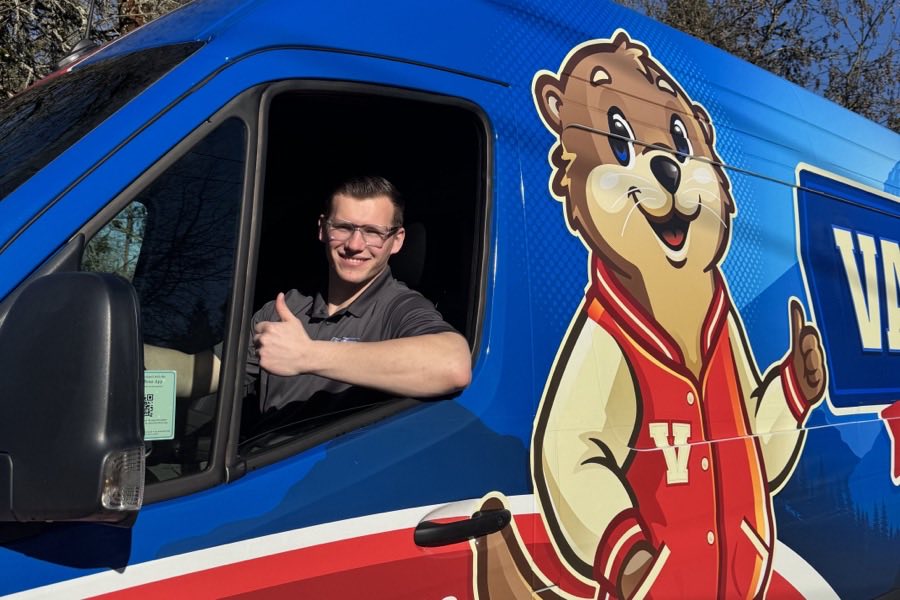 A Varsity Heating and Cooling technician giving a thumbs up from the window of a marked Varsity vehicle.